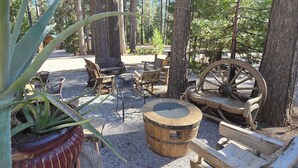 A rustic outdoor seating area with wooden benches, a wooden barrel, and a large wooden wheel.