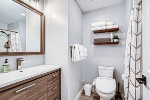A bathroom with a white sink, a mirror, a toilet, and a shower curtain. - Modern DTC King Studio with Wet Bar, Pool, Light Rail (Greenwood Village)