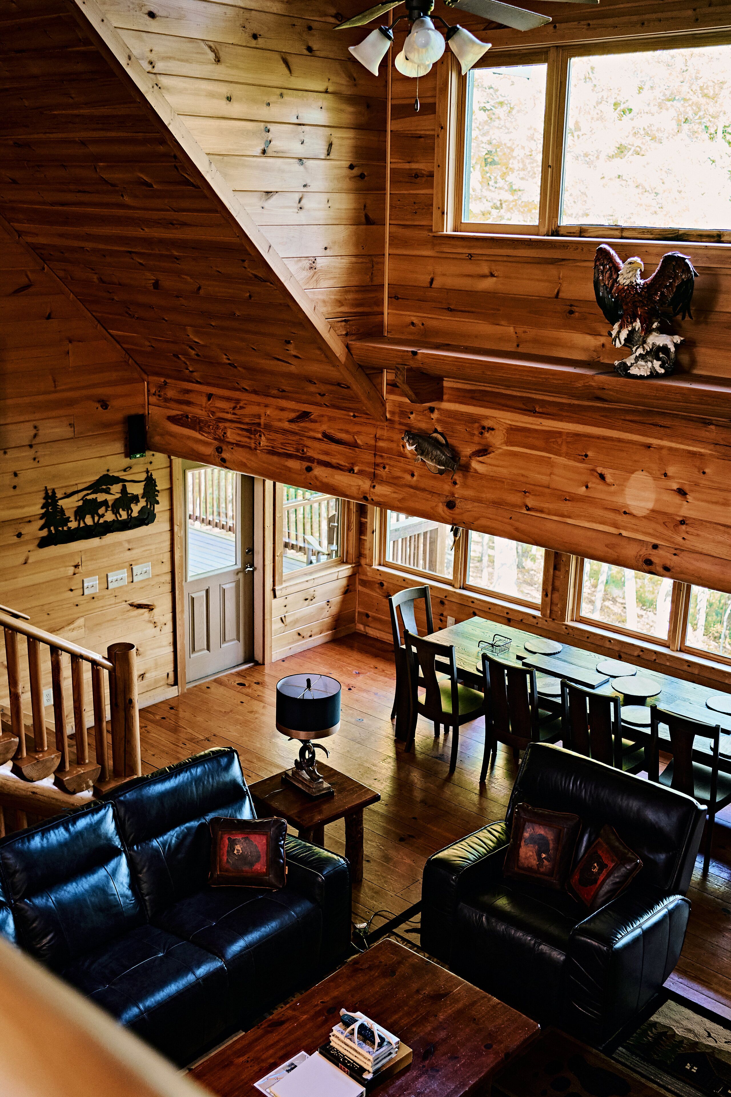 L’intérieur d’un chalet en bois comprend un coin repas, des canapés en cuir et un escalier.