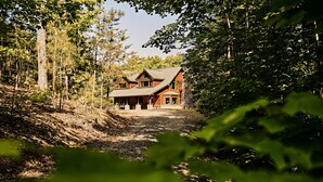 Ein großes Holzhaus, umgeben von dichtem Wald.