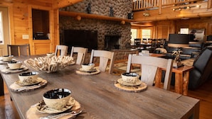 Ein Holzespeisesaal mit Schüsseln und Tellern, ein Steinkamin und eine Holzzahl.