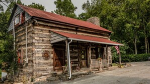 A rustic log cabin with a metal roof and a porch.