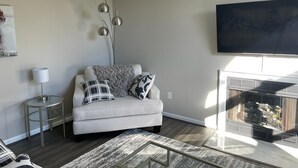 Ein Wohnzimmer mit einer Couch, einem Beistelltisch, einer Lampe, einer Stehlampe und einem Kamin.