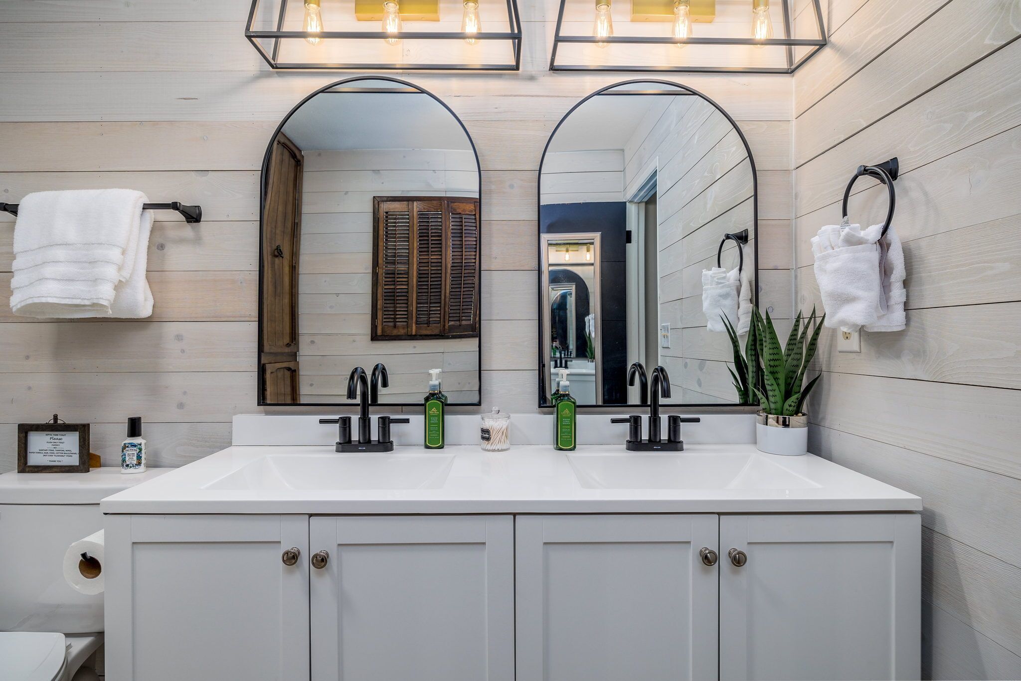 A bathroom with a double sink, two mirrors, and a towel rack.