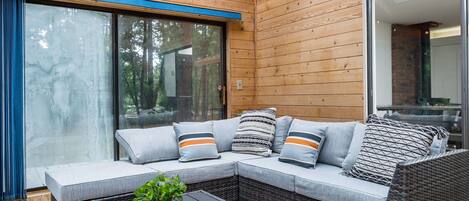 A modern outdoor seating area with a wicker sofa, cushions, and a small table with a plant.