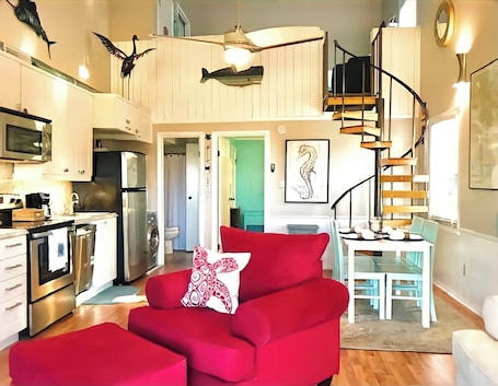 A compact living space with a kitchenette, a dining area, and a staircase.