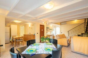 Un coin repas avec une table dressée pour quatre personnes, un canapé et un escalier.