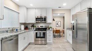 A modern kitchen with white cabinets, stainless steel appliances, and a granite countertop. - Modern Cactus  - Heated Pool and Hot Tub (Peoria)