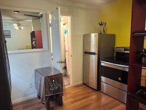 A compact kitchen with a refrigerator, stove, and a small dining table.