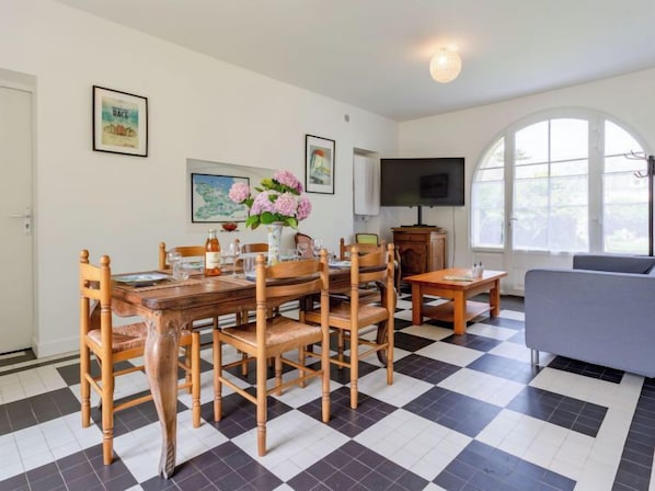 Un coin repas avec un sol à carreaux, des meubles en bois et un téléviseur fixé au mur.