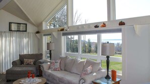 A living room with a sofa, armchair, and a table with candles. - Sunset Waterview Cottage w/Fire Pit Near Acadia (Ellsworth)