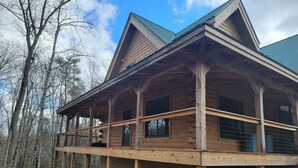 A log cabin with a covered porch and multiple windows.