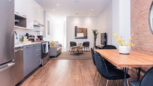 A modern kitchen with a dining area, a TV, and a brick wall. - Vast and perfectly located 3 bedroom flat by Denstays (Montréal)