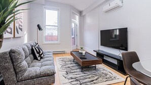 A modern living room with a grey sofa, a coffee table, a TV, and a plant. - New classy 2 bedroom apartment in Le Plateau by Denstays (Montréal)