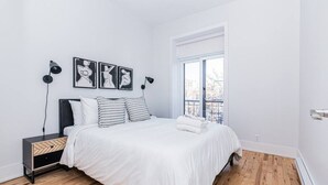 A minimalist bedroom with a bed, a nightstand, and a window. - New classy 2 bedroom apartment in Le Plateau by Denstays (Montréal)