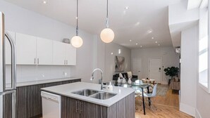A modern kitchen with a central island, stainless steel appliances, and pendant lighting. - Welcoming and Homey unit near Mount Royal by DenStays (Montréal)
