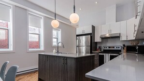 A modern kitchen with a central island, stainless steel appliances, and pendant lighting. - Welcoming and Homey unit near Mount Royal by DenStays (Montréal)