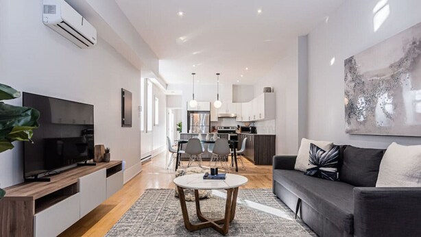 A modern living room with a flat-screen TV, a grey sofa, and a coffee table. - Welcoming and Homey unit near Mount Royal by DenStays (Montréal)