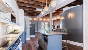 A modern kitchen with dark wood flooring, stainless steel appliances, and a central island.