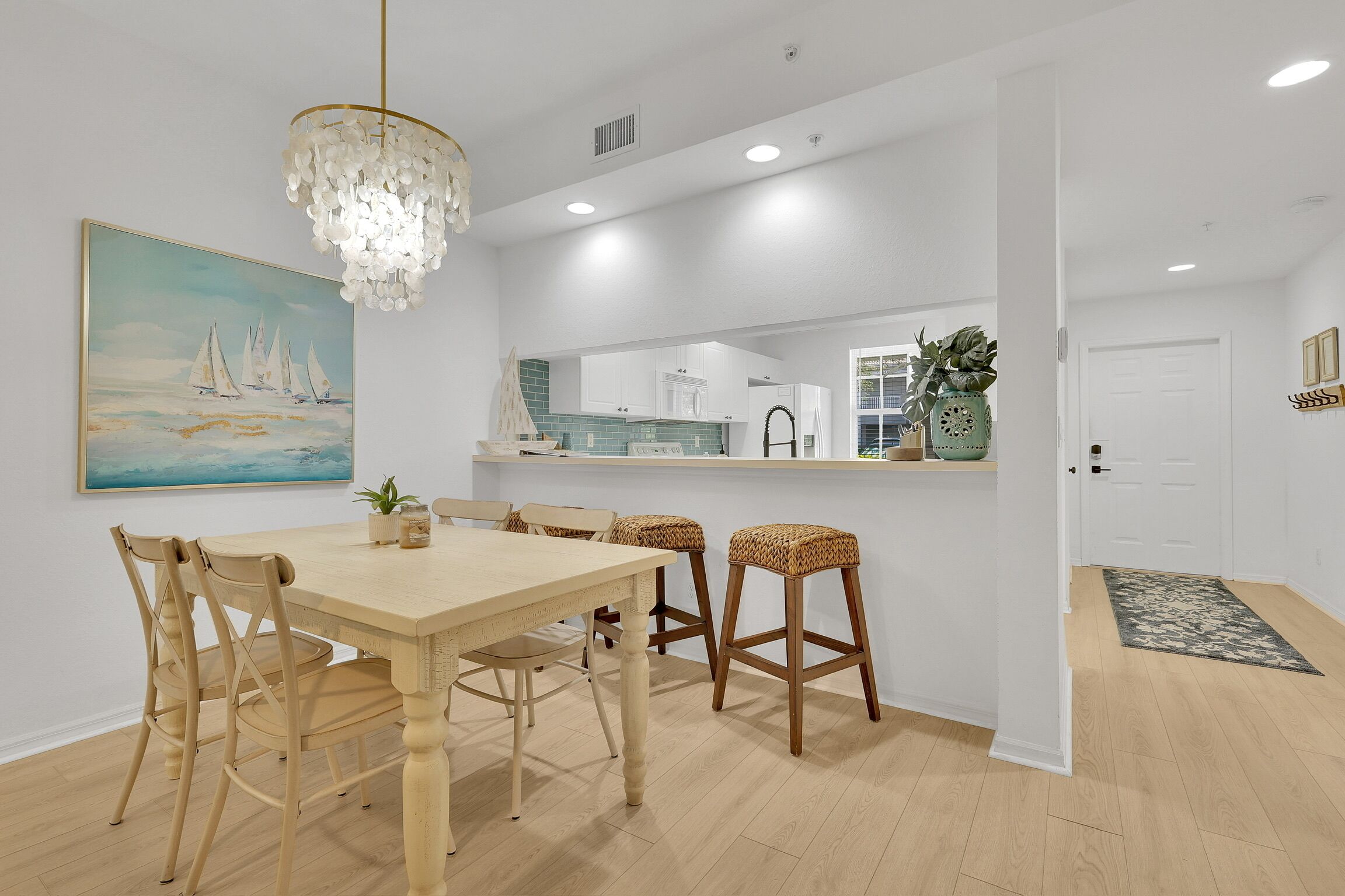 Een moderne keuken met witte kasten, een houten eettafel en een kroonluchter.