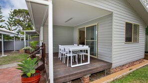 A covered patio with a white table and chairs, a brick pathway, and a potted plant. - Hanalei - Pet Friendly - Directly Opposite Waterfront (Myola)