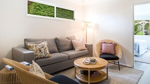 A cozy living room with a grey sofa, a wicker chair, a round coffee table, and a floor lamp. - Hanalei - Pet Friendly - Directly Opposite Waterfront (Myola)