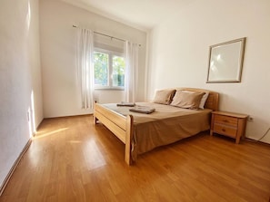A bedroom with a wooden bed, a nightstand, a window with curtains, and a framed picture on the wall. - Luxury Villa With Pool & Jacuzzy 8 Min from Mostar (Mostar)