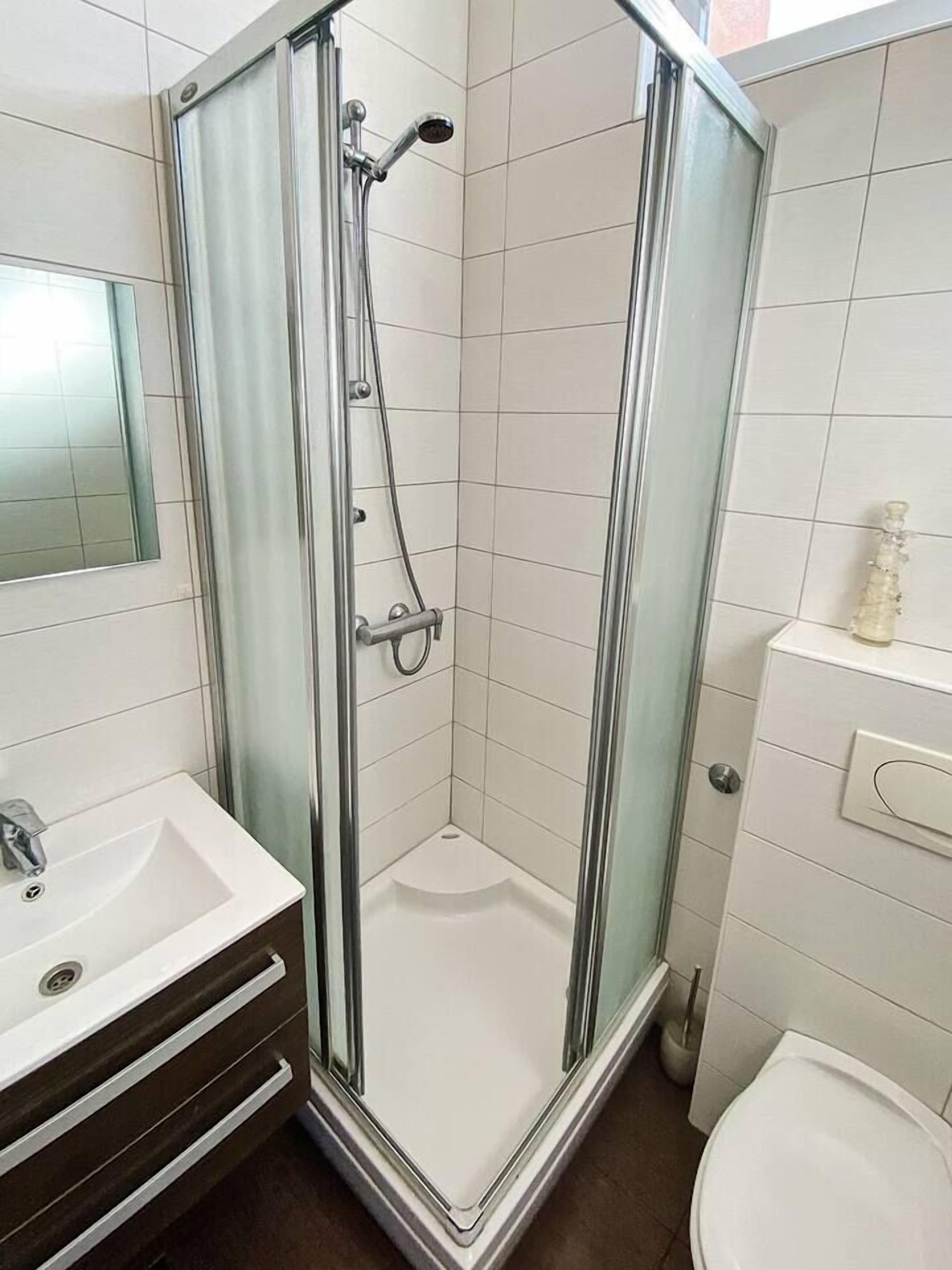 A bathroom with a glass-enclosed shower, a sink, and a toilet.
