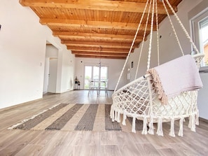 A spacious room with a high wooden ceiling, a hanging macrame chair, and a dining area in the background. - Luxury Villa With Pool & Jacuzzy 8 Min from Mostar (Mostar)