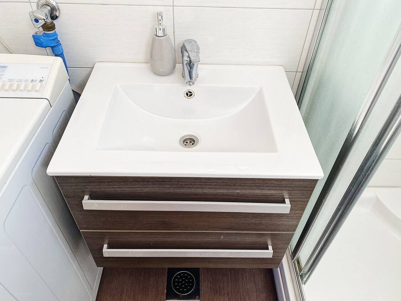 A bathroom with a white sink, a mirror, and a shower area.