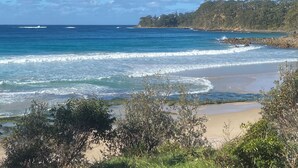 A coastal landscape with a beach, ocean waves, and a forested hill. - Modern Self Contained Studio at Narrawallee Beach (Narrawallee)