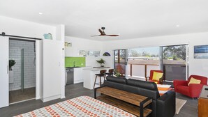 Una habitación moderna y bien iluminada con una cama grande, un sofá, un comedor y una cocina.