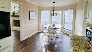 A dining area with a round table and chairs, a chandelier, and a fireplace with a white brick wall in the background. - THE BRIAR Beautiful spacious home in quiet neighborhood. Close to dining and shopping! Broadway Ave. (Tyler)