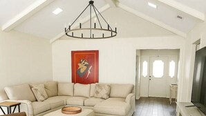 A spacious living area with a high ceiling, a large sofa set, a brown leather armchair, and a wooden coffee table. - THE BRIAR Beautiful spacious home in quiet neighborhood. Close to dining and shopping! Broadway Ave. (Tyler)