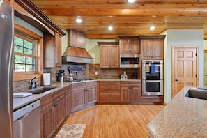A kitchen with wooden cabinets, stainless steel appliances, and a granite countertop.