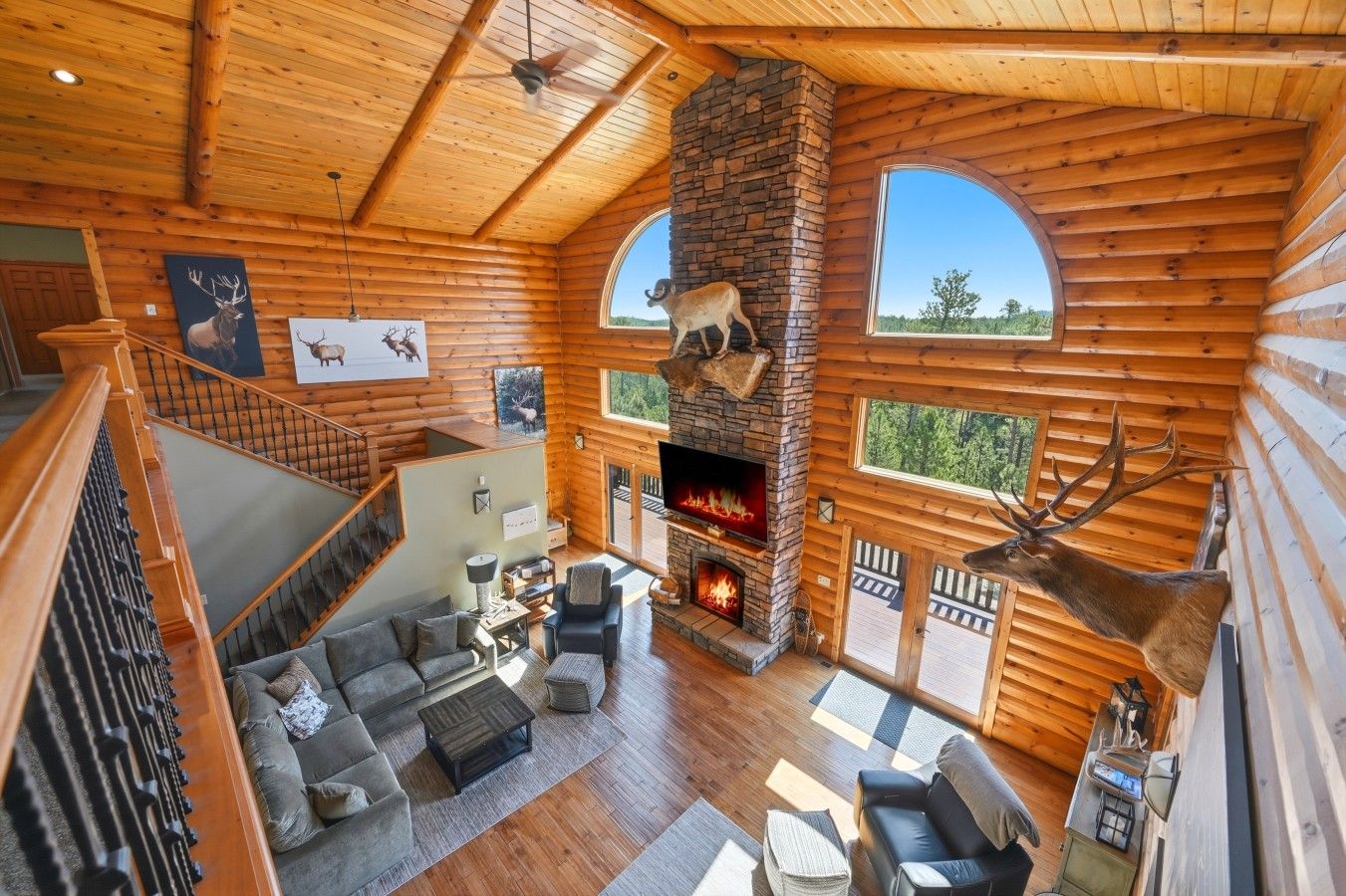 L’intérieur d’une cabane en rondins, avec une cheminée, un escalier et un coin repas.