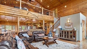 A spacious living area with leather sofas, a wooden coffee table, and a staircase leading to an upper level.