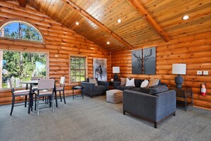 A log cabin interior with a dining area, sofas, and artwork.