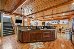 A spacious kitchen with a large island, wooden cabinets, and a stone backsplash.