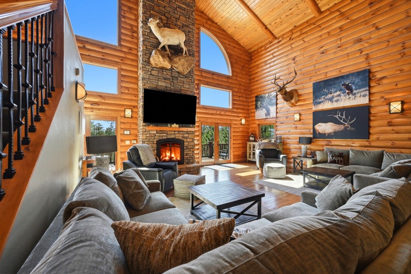 A spacious living room with a fireplace, comfortable seating, and wooden walls.