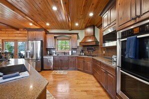 A modern kitchen with wooden cabinetry, stainless steel appliances, and a large island.