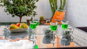 A glass table with green drinks, a bowl of fruit, and potted plants. - Rinconada Real by Interhome (Benidorm)