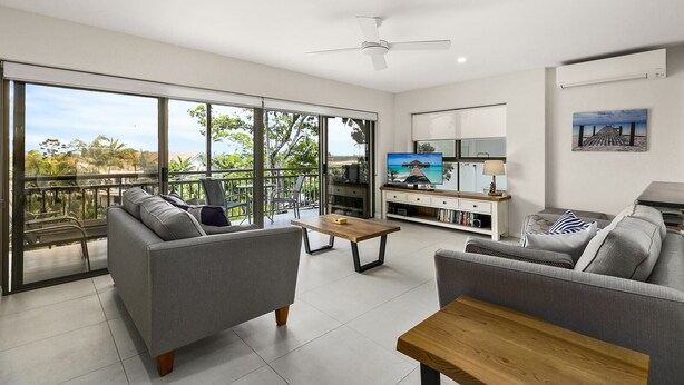 A modern living room with a balcony, a flat-screen TV, and a dining area.