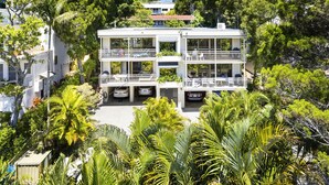 A multi-story building with balconies, surrounded by lush greenery.