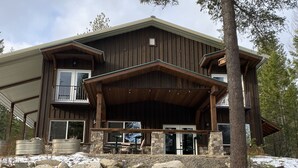A large wooden house with a covered porch, stone foundation, and a stone wall in front. - Entire guesthouse, quiet wooded area of Cocolalla (Cocolalla)