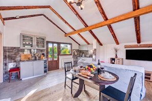 A spacious kitchen with modern appliances, a dining area with a round table, and a living space with a sofa and a flat-screen TV.