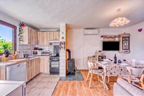 A modern kitchen with wooden cabinets, a dining area with a table set for two, and a built-in TV.