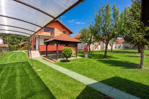 A residential property with a covered patio, a well-maintained lawn, and a small tree.