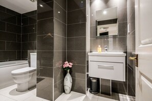 Een bad/douchecombinatie, een haardroger, handdoeken, zeep