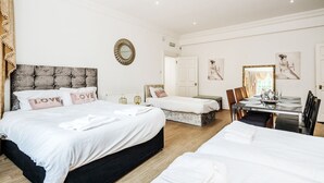 A hotel room with two beds, a dining table, and a mirror.
